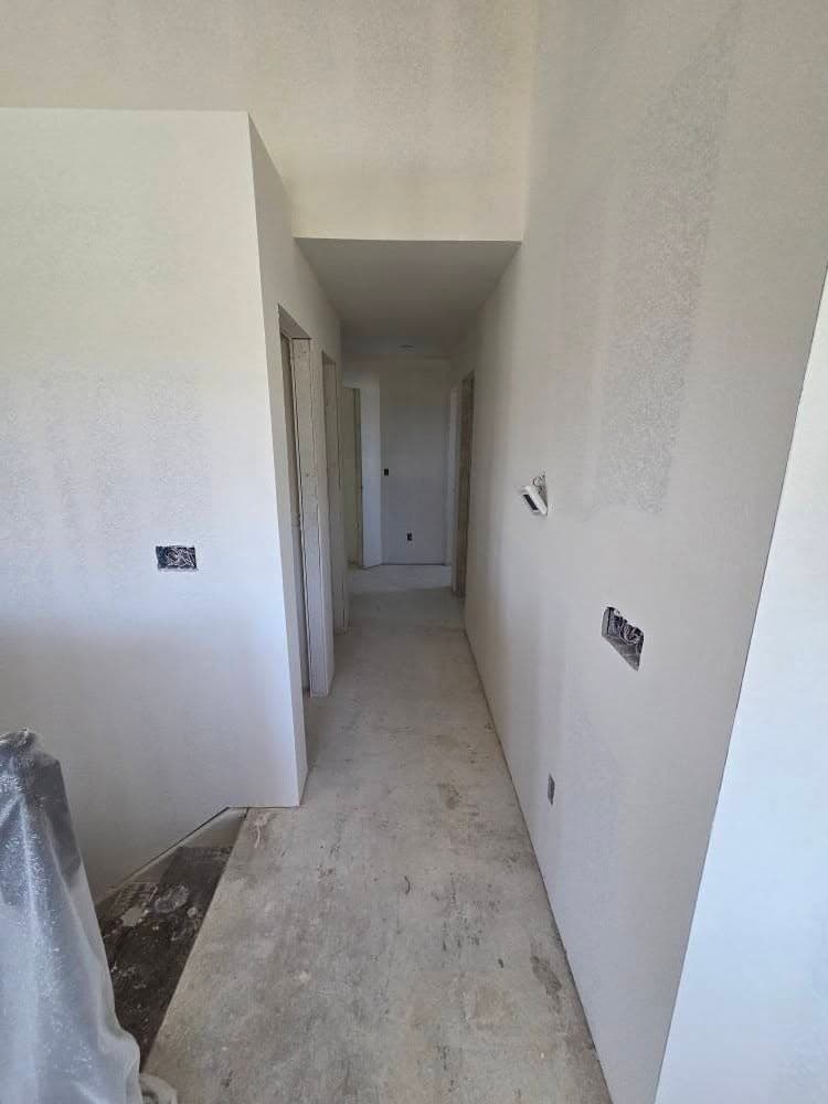 Narrow hallway with white drywall walls and electrical outlet boxes