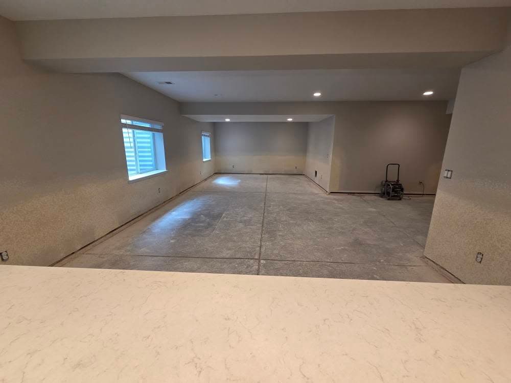 Large empty room with drywall walls and recessed ceiling lights